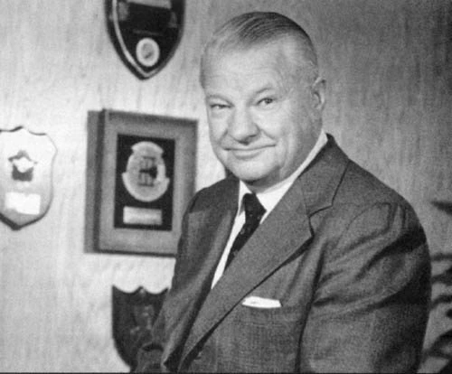 Black-and-white portrait of Kelly Johnson, smiling in a suit
