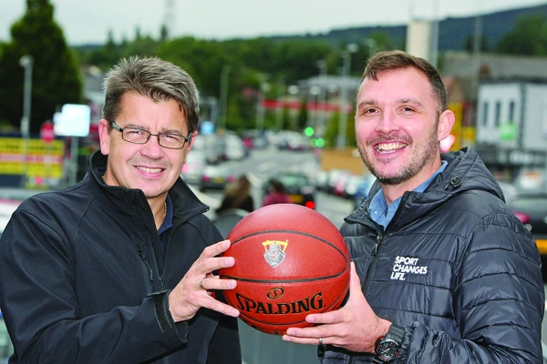 Two men, including Gareth Maguire, holding a basketball outdoors in a sports charity setting